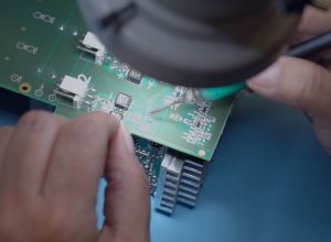 Two hands soldering on a circuit board