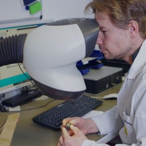 A man in a lab coat looking into a microscope