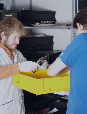 Two men packing a box with electrical components